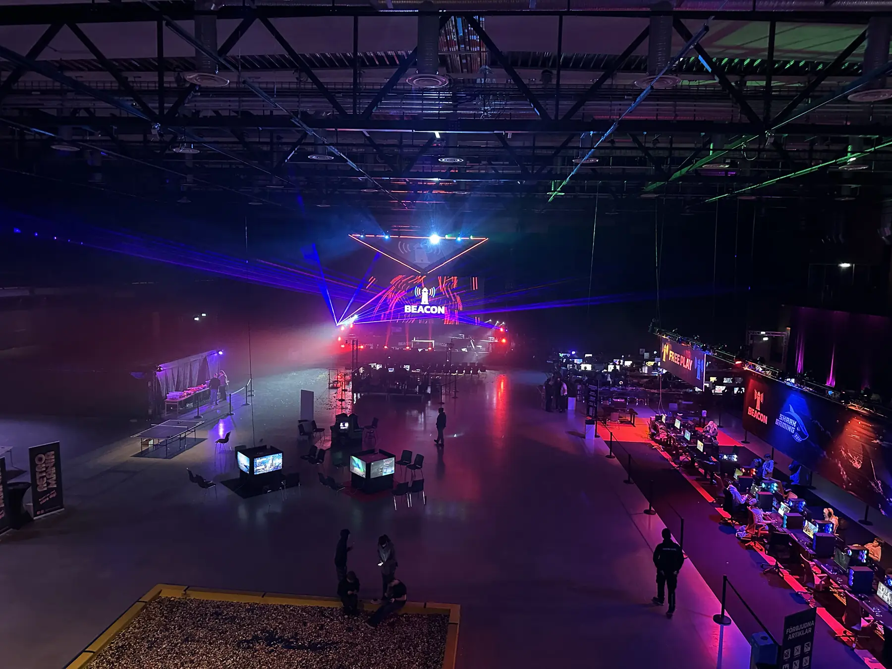 Conventums hall sedd från balkongen, med lasrar över scenen och upplysta free play-platser längs väggen.